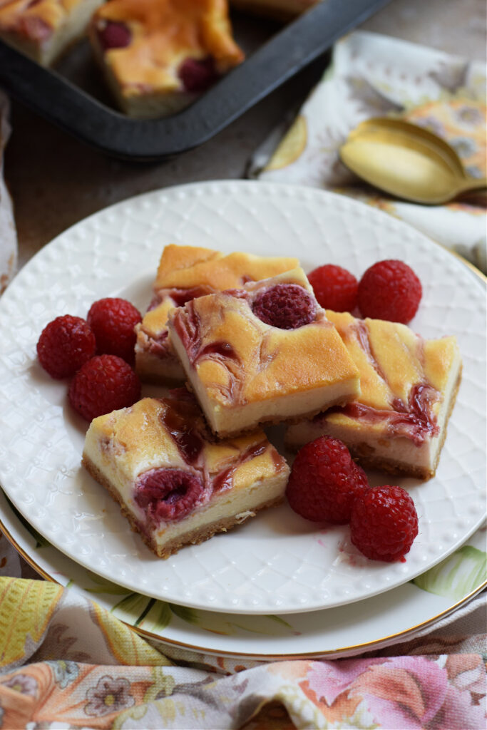 Raspberry cheesecake bars on a white plate.