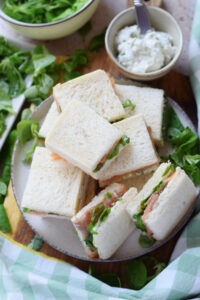 Small smoked salmon sandwiches on a plate.