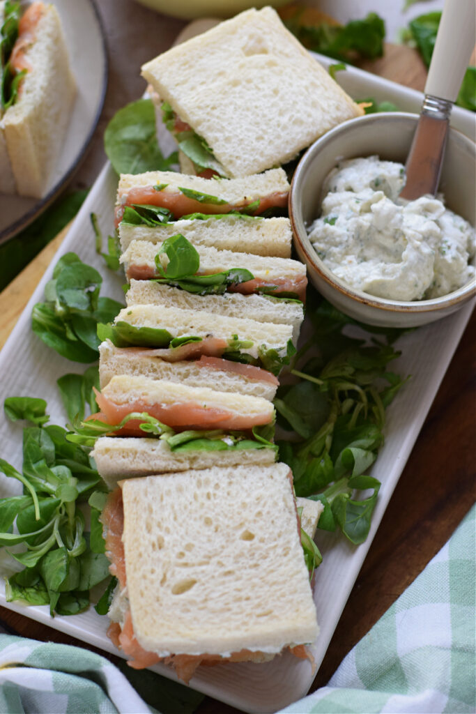 Smoked salmon sandwiches on a small white plate.