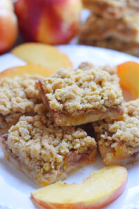 Peach crumble bars on a white plate.