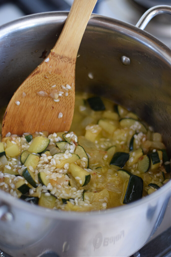 Adding broth to risotto in a pot.