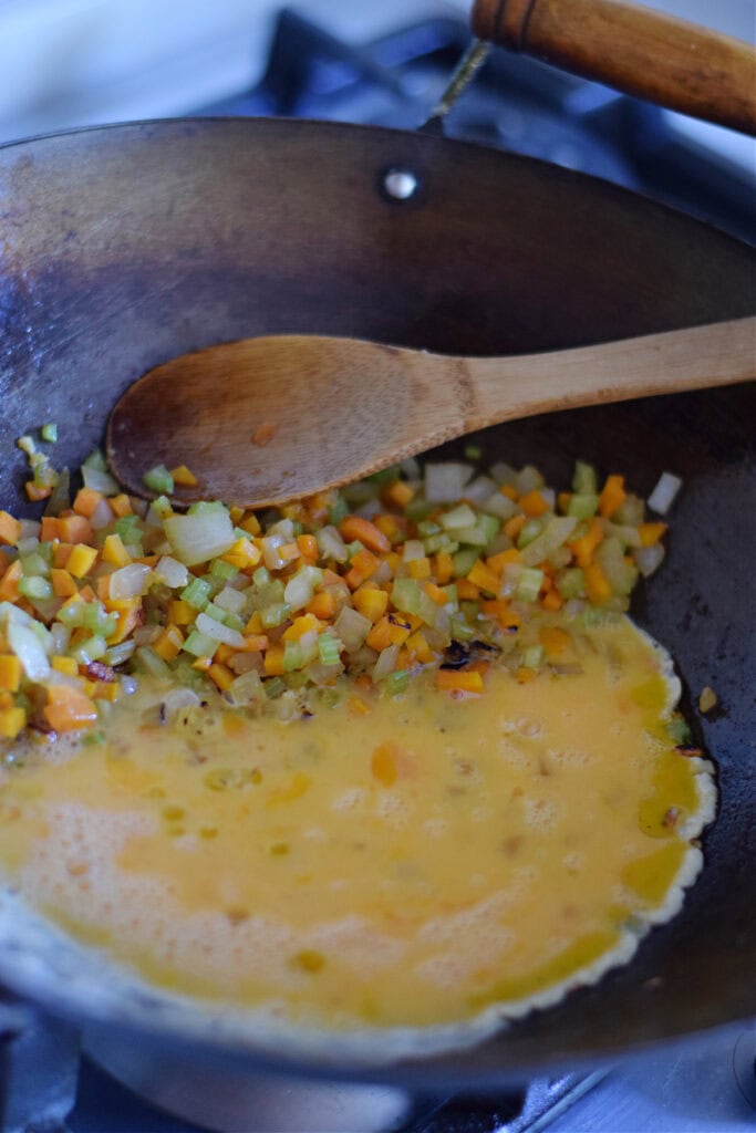 Cooking eggs with vegetables in a wok.