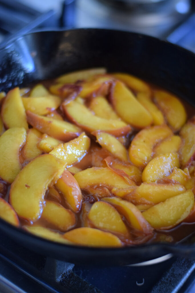 Cooked peaches in a skillet.