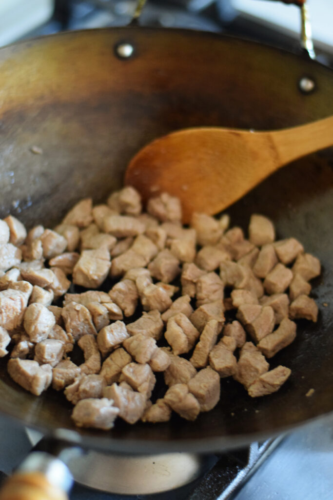 Cooked pork cubes in a wok.