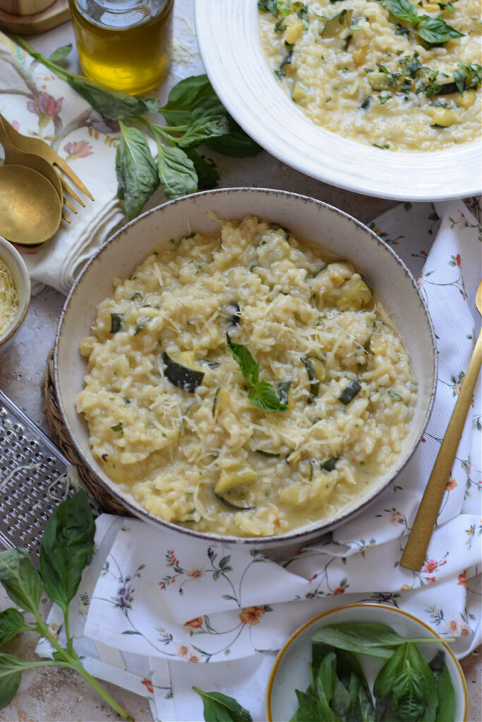 Creamy rice with parmesan cheese and zucchini in white serving bowls.