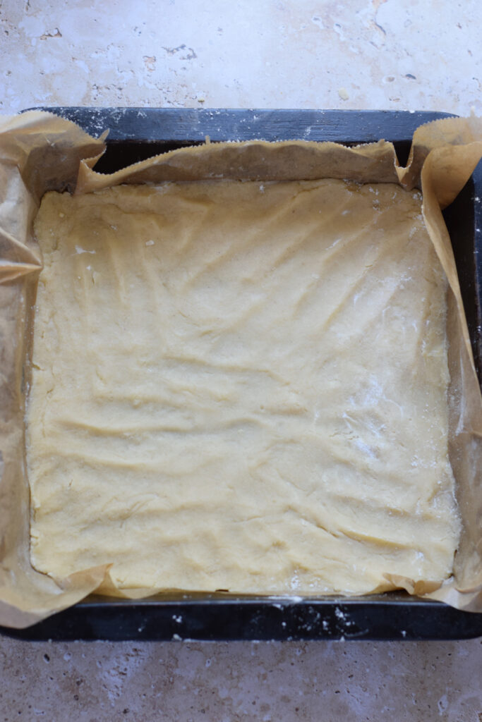 Ready to bake shortbread cookie base in a baking tin.