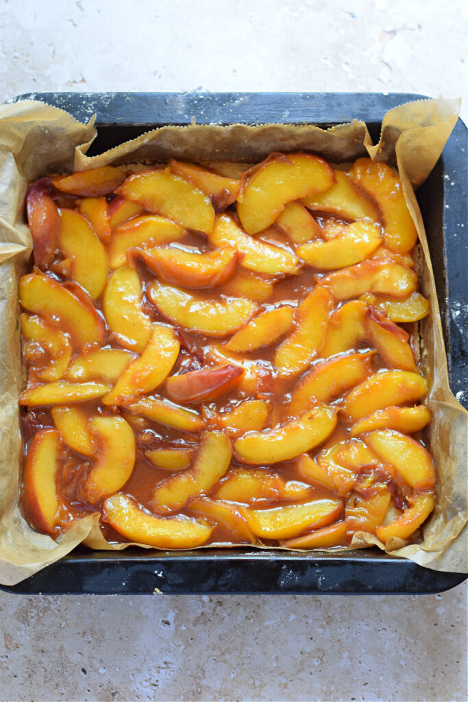 Making peach crumble squares in a baking dish.