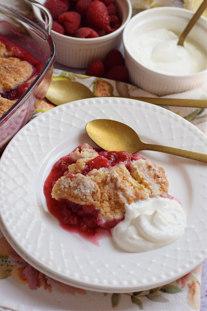 Raspberry cobbler on a plate with cream.