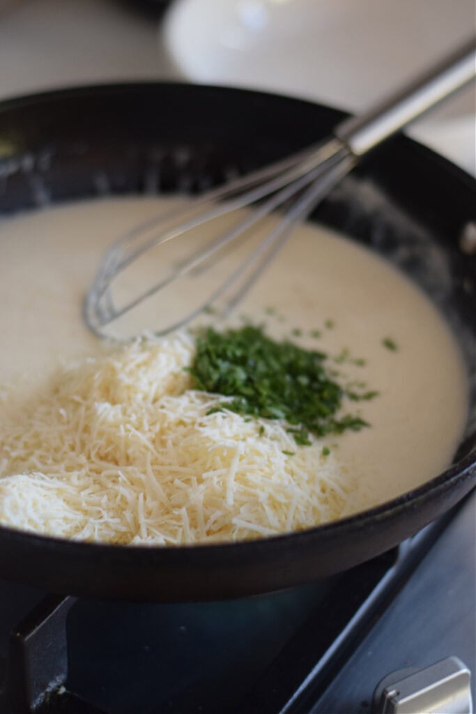 Making a cheese sauce for pasta in a skillet.