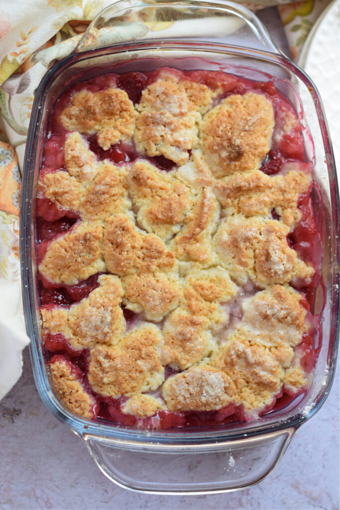 Baked raspberry cobbler in a glass dish.