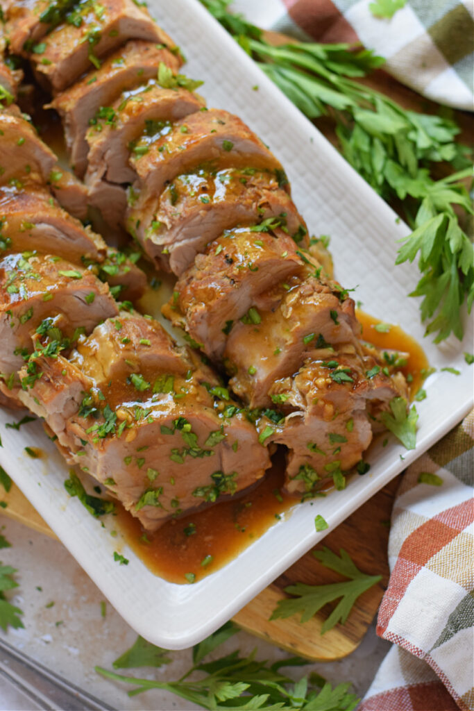 close-up-slow-cooker-pork-tenderloin-image Close up of a pork tenderloin on a white serving plate.