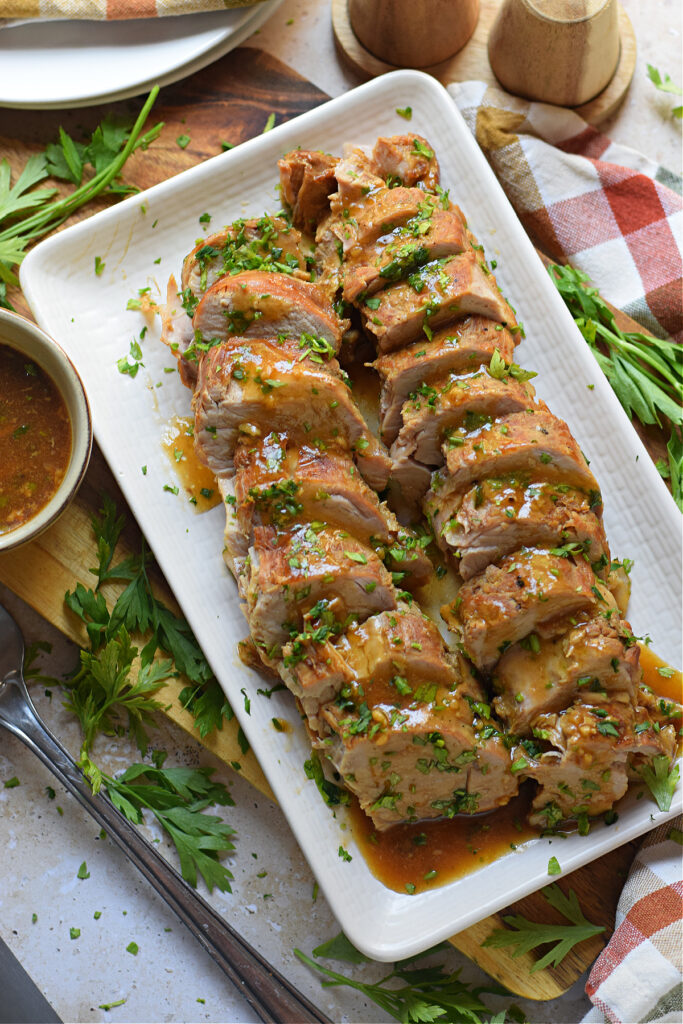 Slow cooker pork tenderloin on a white plate.