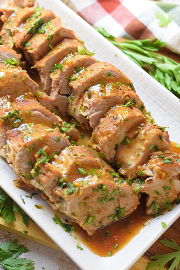 Slow cooked pork tenderloin on a white plate.