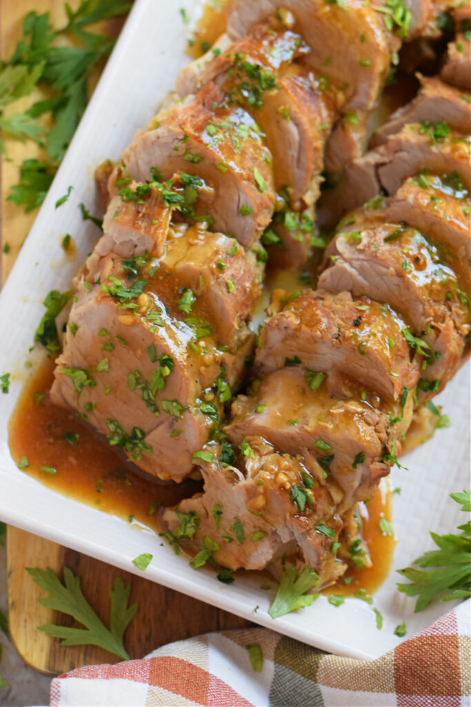Close up of pork tenderloin on a white plate.
