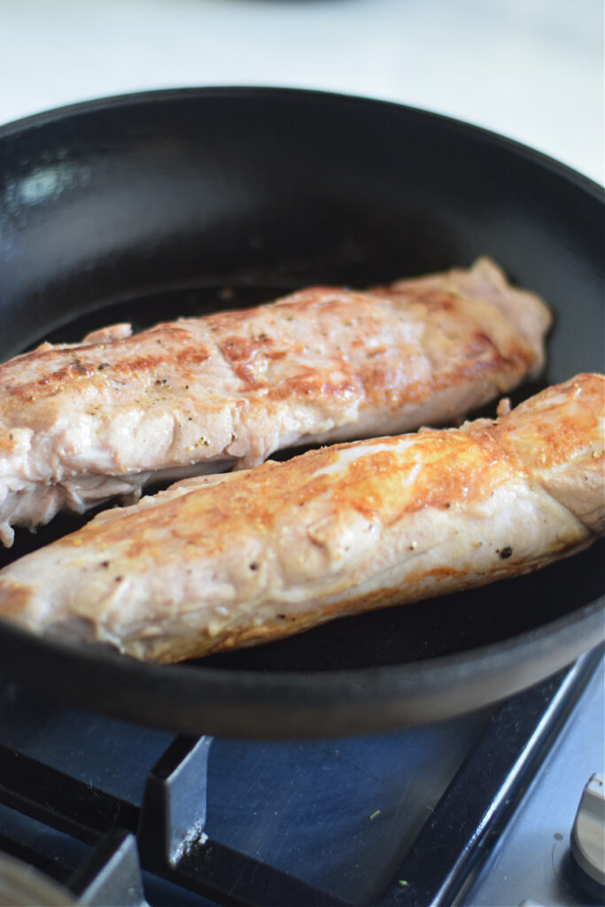 Searing pork in a skillet.
