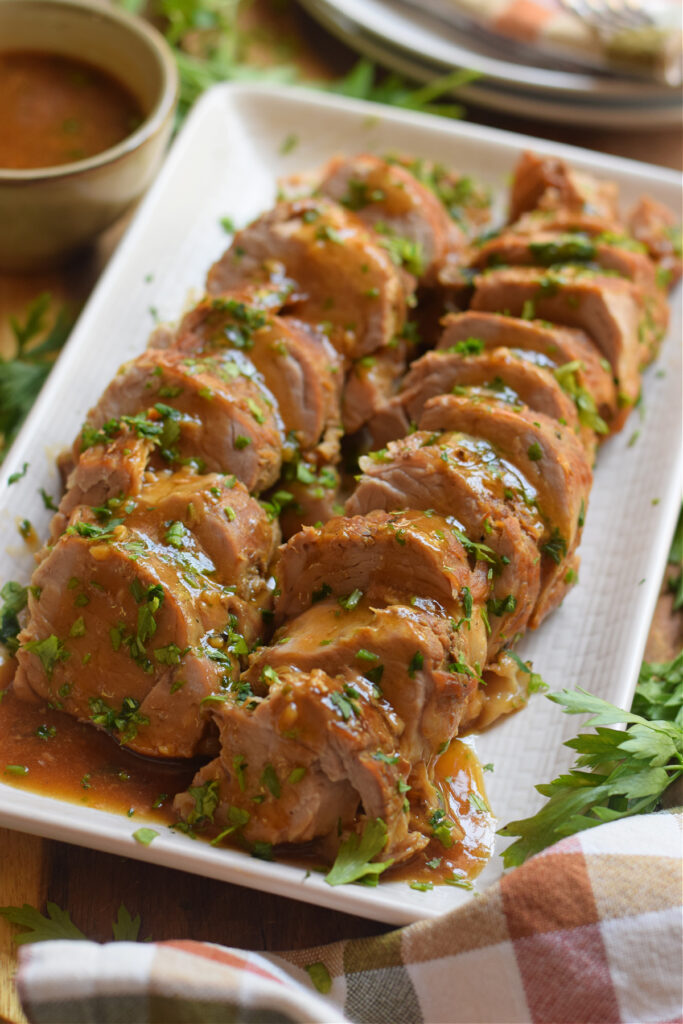 Slow cooker pork cut into pieces on a white plate.