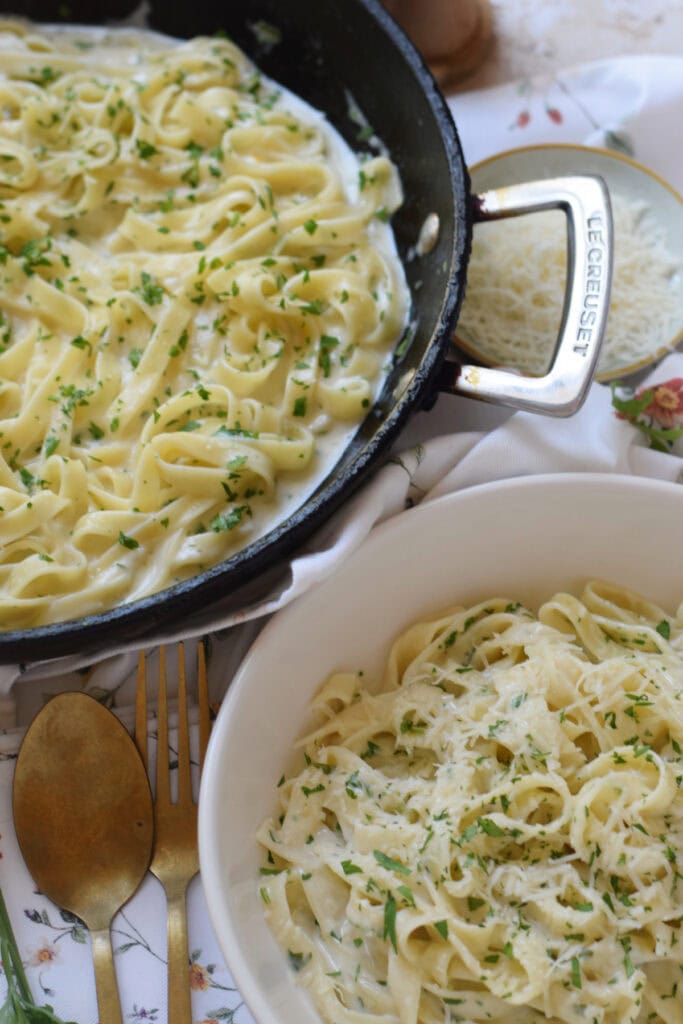 Creamy garlic parmesan pasta in a skillet and a bowl.