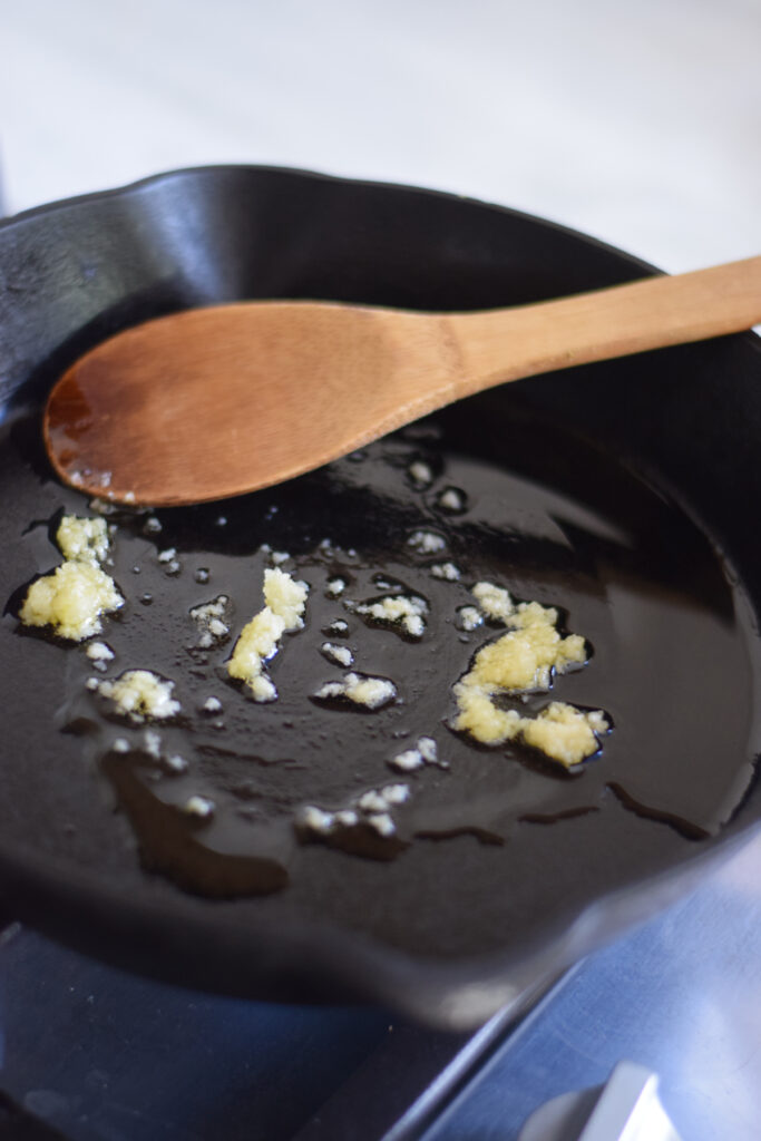 Adding garlic to a skillet.