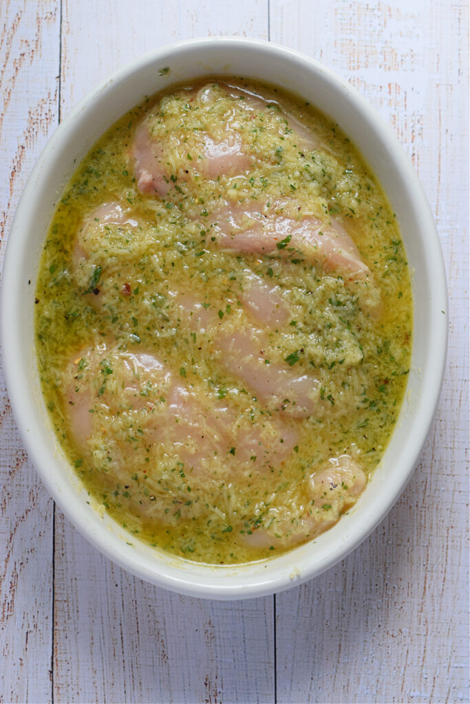 Marinaded chicken in a white bowl.