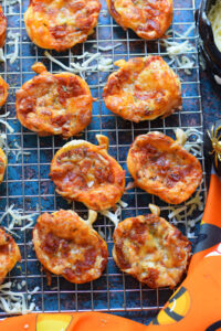 Halloween puff pastry mini pizzas on a baking tray.