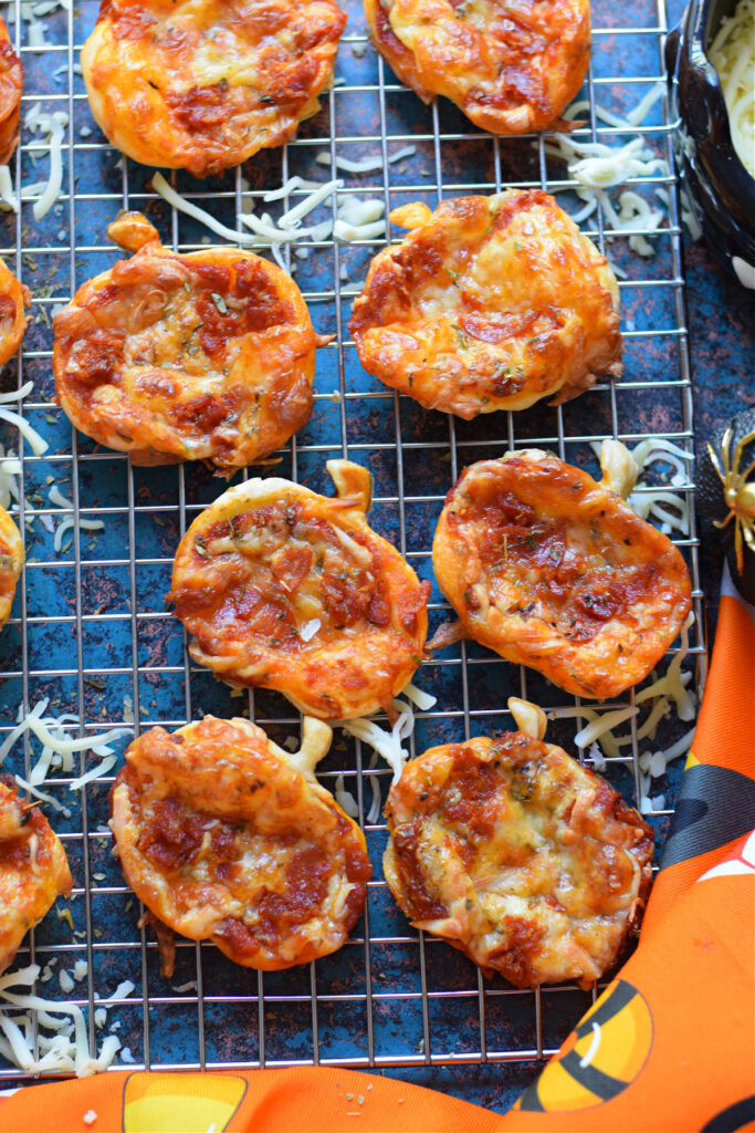 Halloween puff pastry mini pizzas on a baking tray.