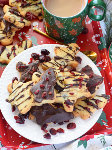 Dark chocolate shortbread cookies on a plate with a cup of coffee.