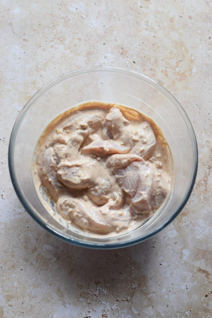 Marinaded chicken in a glass bowl.