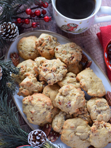 Date and pecan cookies on a cookie plate with a cup of coffee.