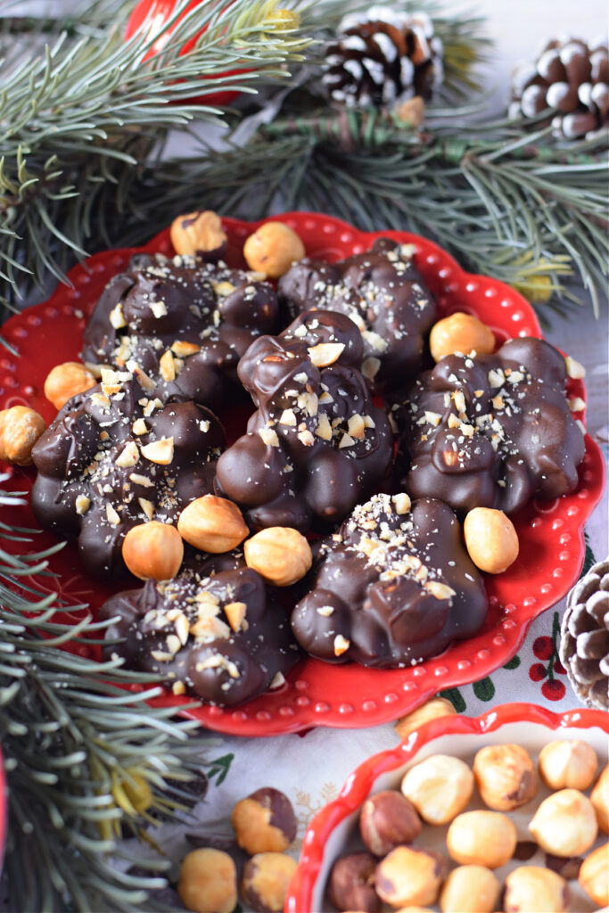 Chocolates with hazelnuts on a red christmas plate.