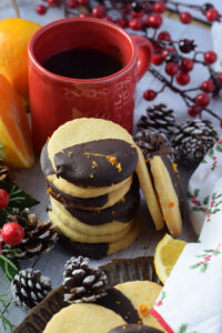 A stack of chocolate orange shortbread cookies with a cup of coffee.