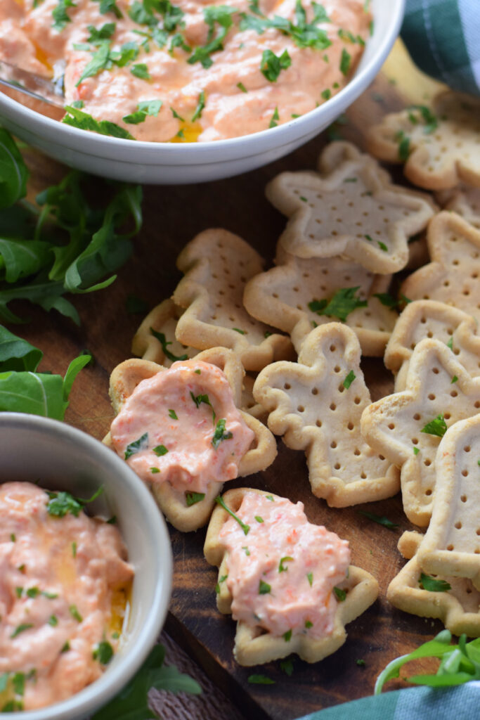 Roasted bell pepper dip with crackers on a plate.