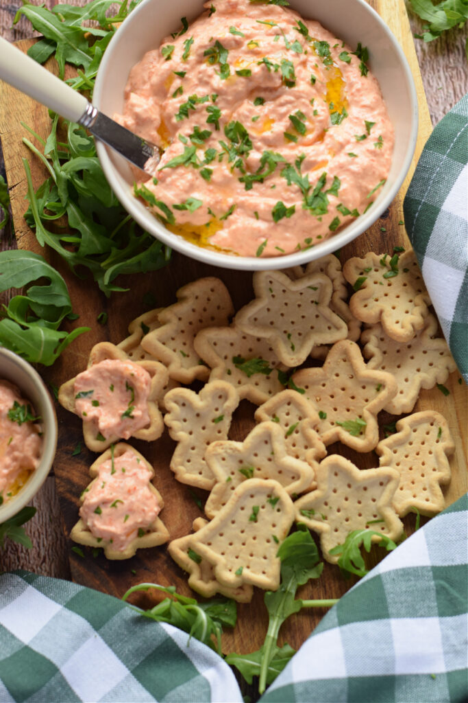 Roasted bell pepper dip with crackers on a tray.