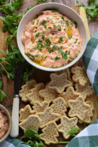 Roasted pepper dip with crackers on a plate.