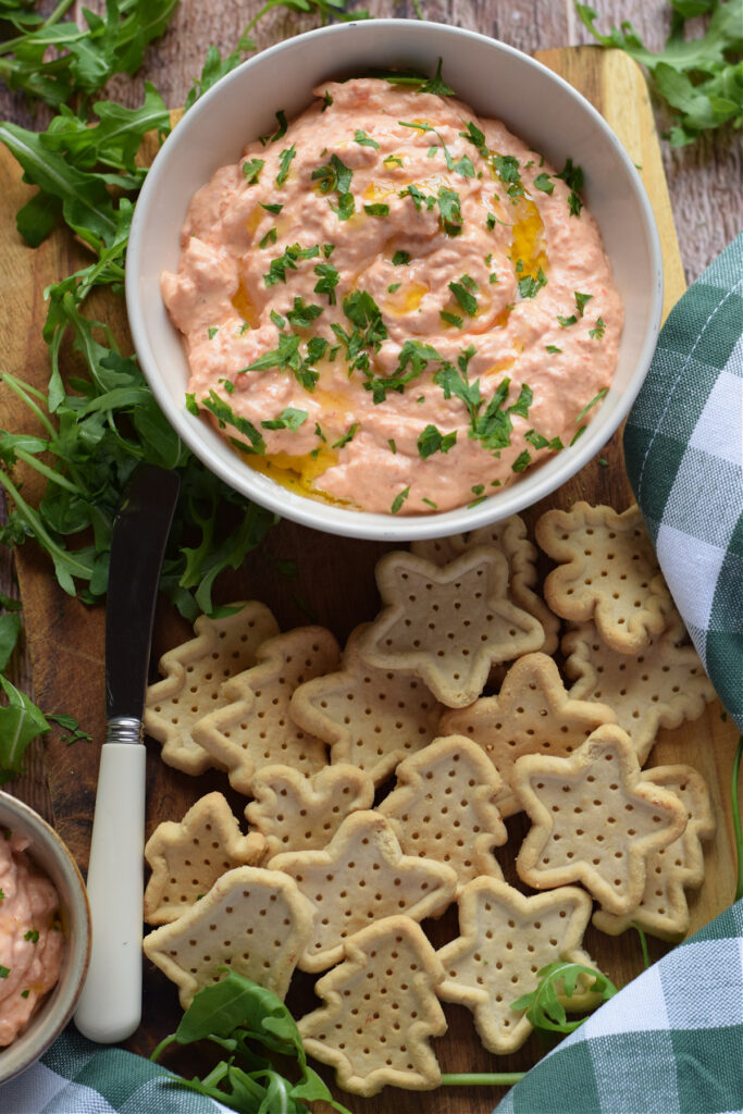 Roasted pepper dip with crackers on a plate.