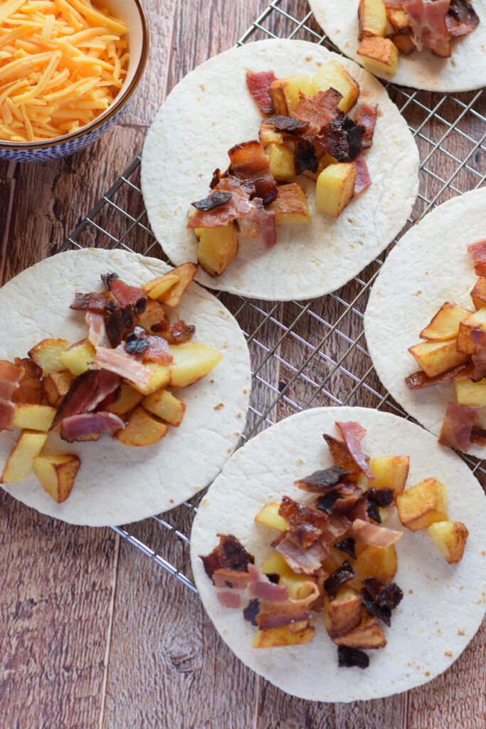 Add bacon and potatoes to tortilla wraps.