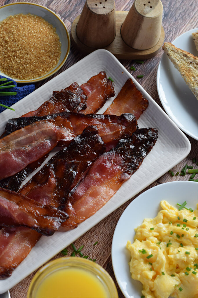 Baked bacon with brown sugar and eggs on the side.