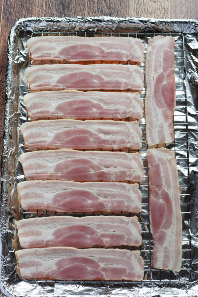 Uncooked bacon on a baking tray.