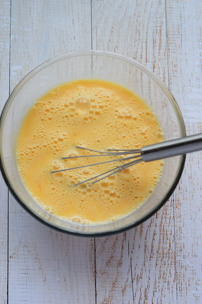 Eggs whisked in a glass bowl.