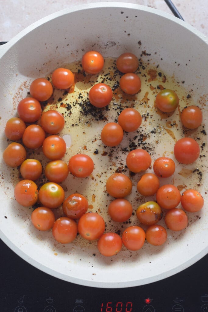 Cooking cherry tomatoes in a skillet.