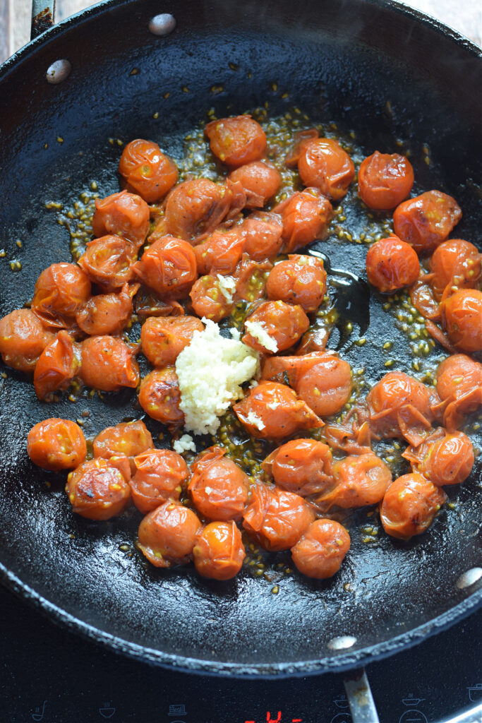 Cooking tomatoes and garlic in a skillet.