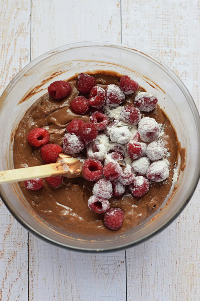Adding raspberries to muffin batter.