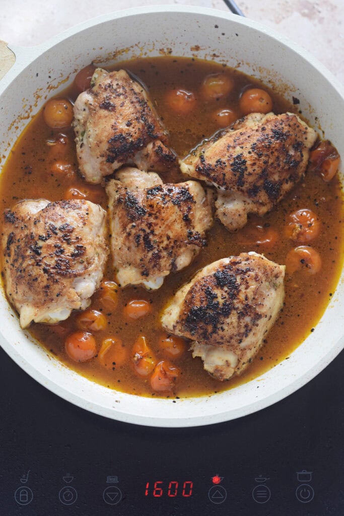 Cooking chicken in a tomato broth.