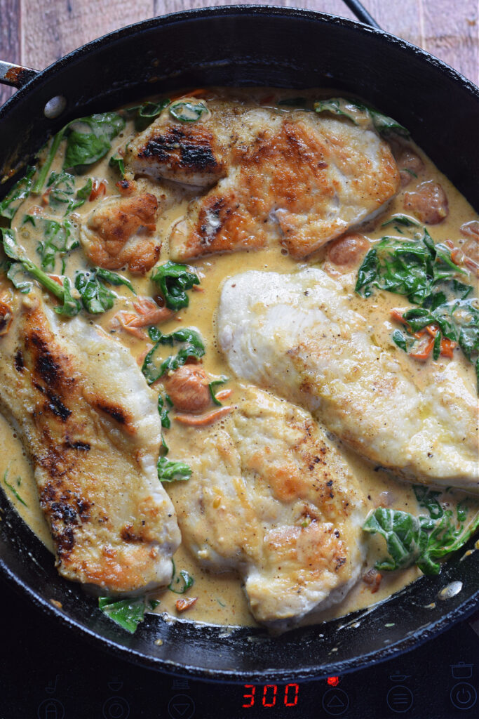 Cooking chicken in a cream sauce in a skillet.