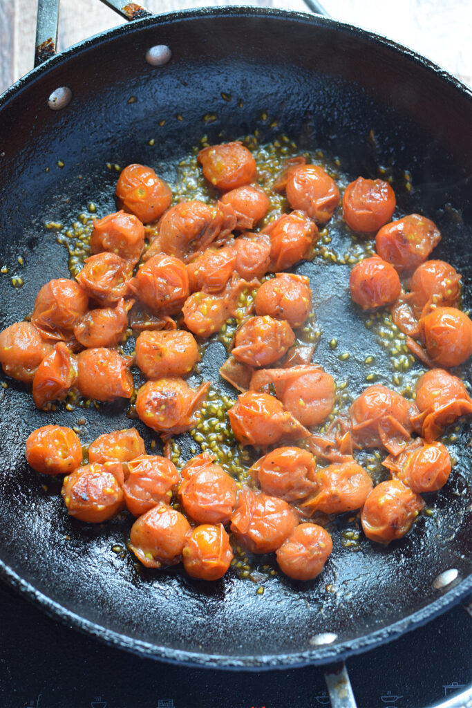 Cooking cherry tomatoes in a skillet.
