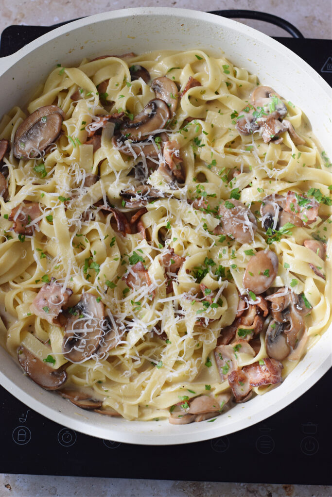 Creamy pasta dish in a white skillet.