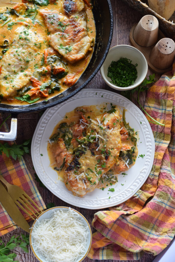 Tomato and spinach chicken on a white plate.