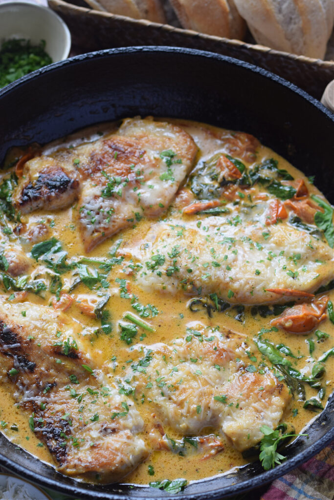 Close up of tomato and spinach chicken in a skillet.