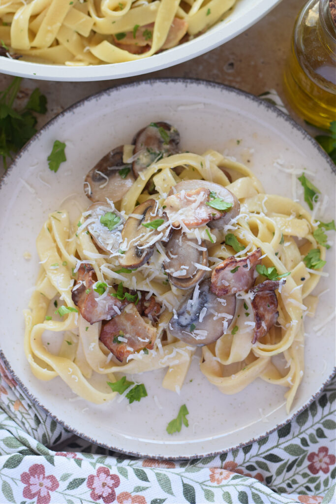 Bacon mushroom tagliatelle on a white skillet.