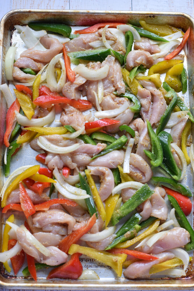 Ready to bake chicken and peppers on a baking tray.