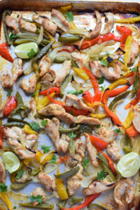 Chicken and peppers on a baking tray.
